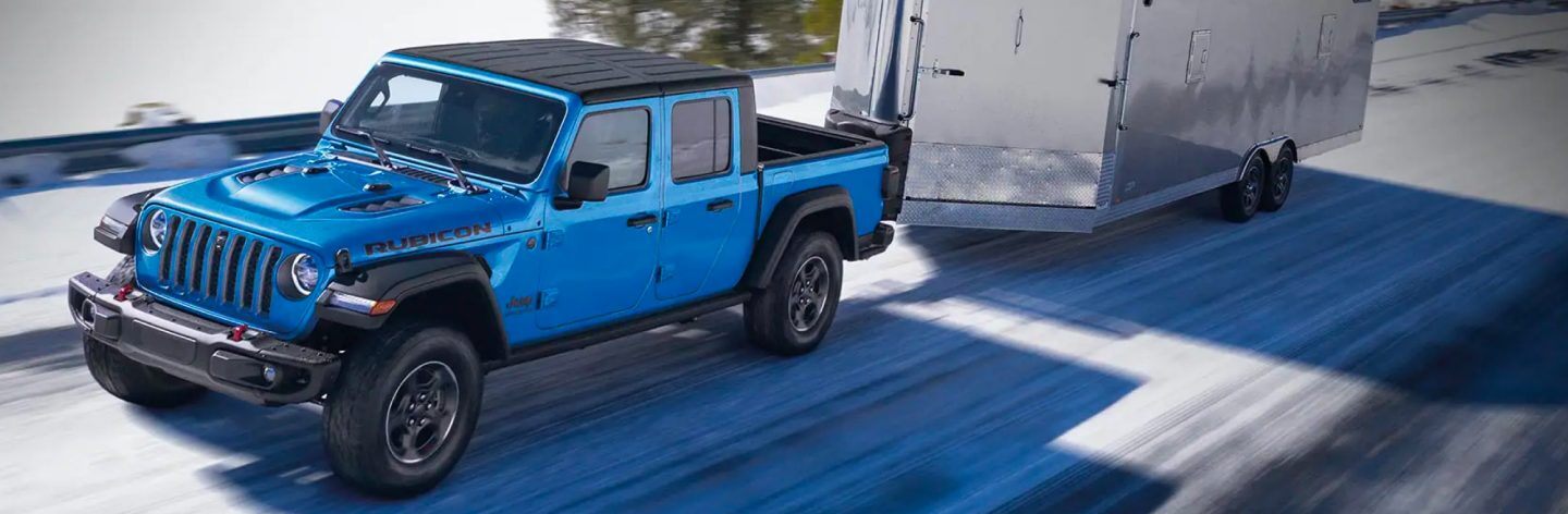 The 2022 Jeep Gladiator Rubicon towing a trailer on a road.