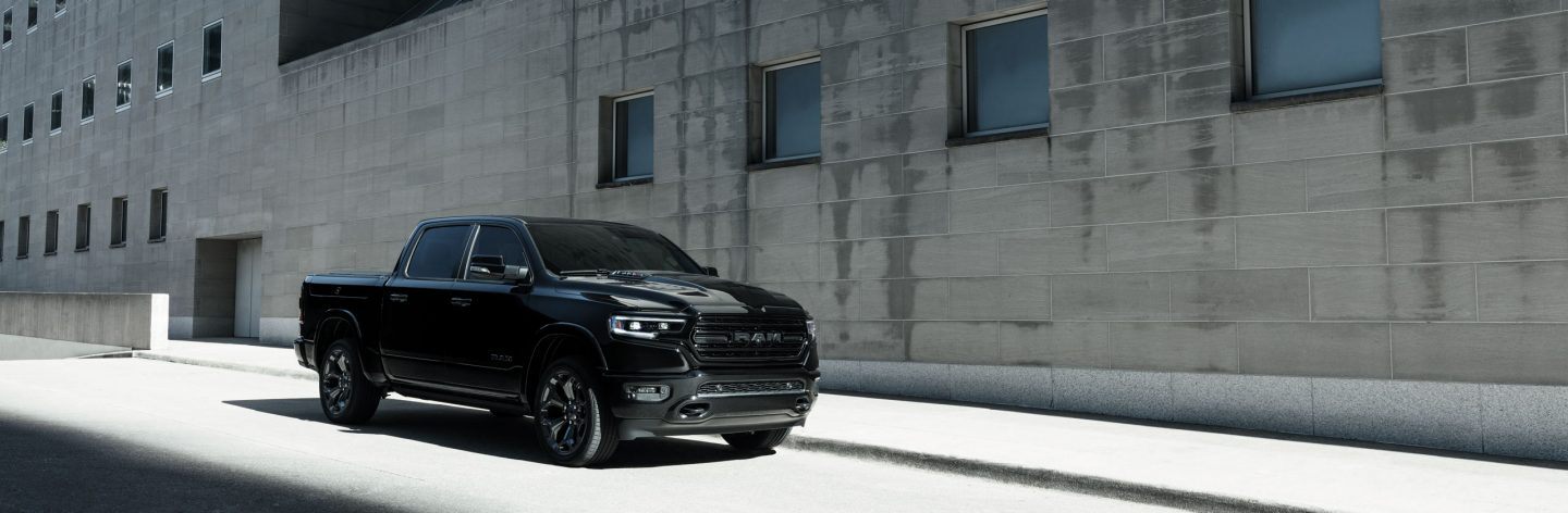 The 2022 Ram 1500 parked on the street beside a featureless gray building.
